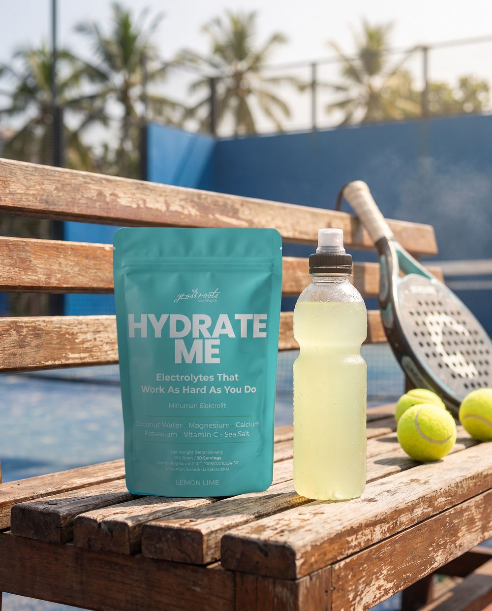 A Hydrate Me pouch and a bottle of the drink on a bench at a padel court